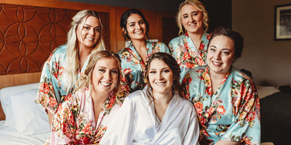 Group of women in a bridal party dressed in gowns getting ready for a wedding